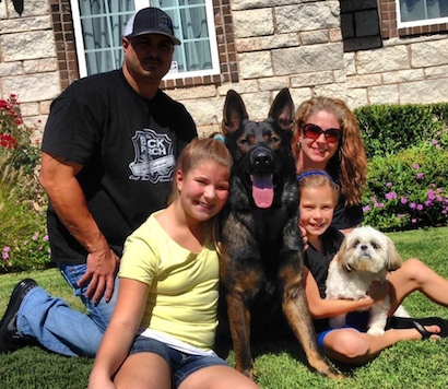 Protection dog sitting in a yard with its family